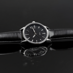 Black wristwatch with a reflective surface on a dark background